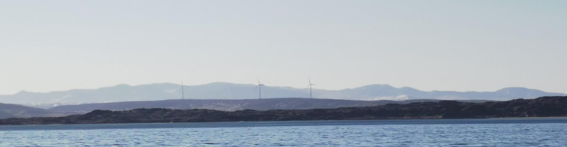 Sea and mountain range on the horizon with wind turbines