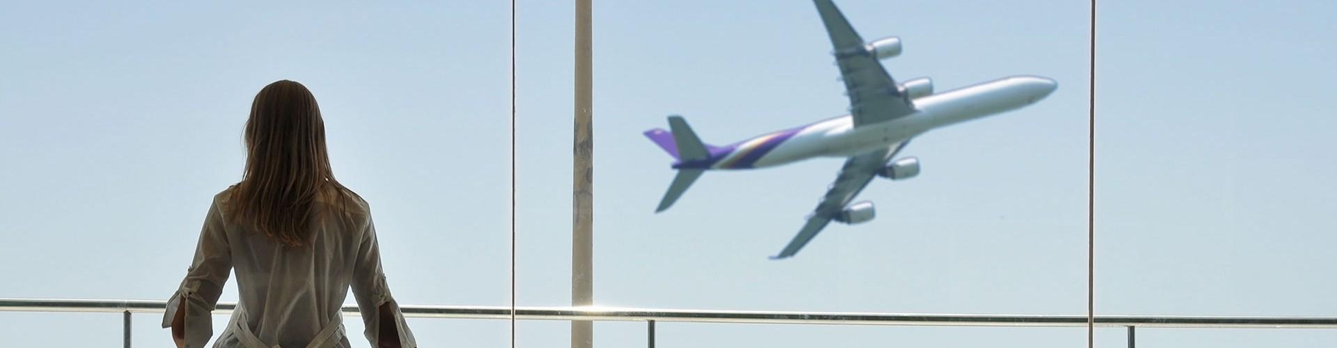 Frau schaut auf startendes Flugzeug