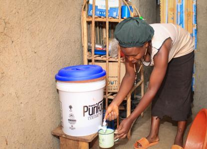 Woman draws water from ceramic water filter